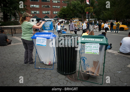 Una donna si regola un riciclo qui segno per una plastica di bottiglie e lattine di alluminio bin in Union Square Park a New York Foto Stock