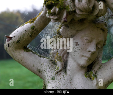 Ragnatela e dewdrop gioielli su un giardino statua - settembre mattina Foto Stock