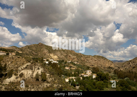 Un pittoresco villaggio Spagnolo, adagiato tra le colline in Andalusia, Spagna sotto luminose, soffici nuvole. Foto Stock