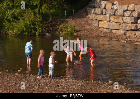 I bambini giocano nel fiume Ehen in Egremont , Cumbria , in Inghilterra , Gran Bretagna , Regno Unito Foto Stock