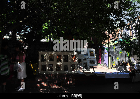 Scena di strada e ballerino di tango dipinti su cavalletti sotto l'ombra di un grande albero, San Telmo mercato domenicale, Buenos Aires Foto Stock