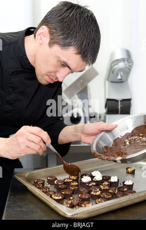 Maschio caucasico chef rende i dolci al cioccolato secondo la propria ricetta Foto Stock