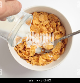 Ciotola di cornflake prima colazione a base di cereali con latte dal versamento di una caraffa. Foto Stock