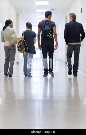 Gli studenti delle scuole superiori a piedi giù il corridoio della scuola, vista posteriore Foto Stock