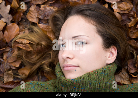 Donna sdraiata in foglie di autunno Foto Stock