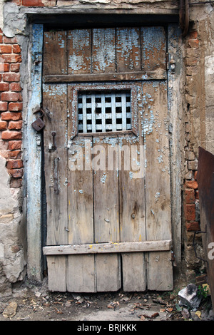 Vecchio weathered porta in legno con barre sulla finestra Foto Stock