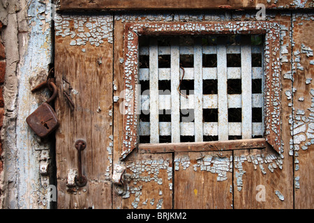 Vecchio weathered porta in legno con barre sulla finestra Foto Stock