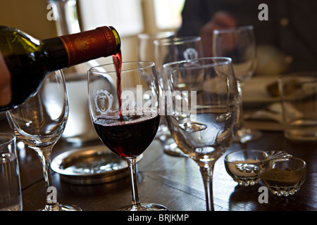 Versando un bicchiere di vino rosso Foto Stock