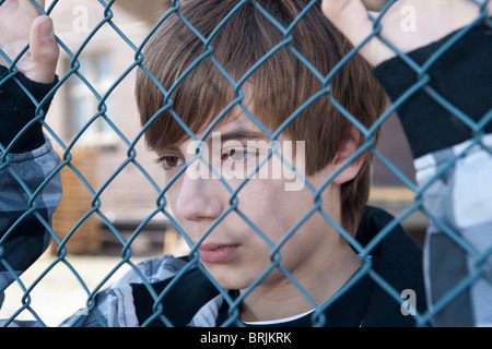 Primo piano del ragazzo adolescente dietro il recinto Foto Stock