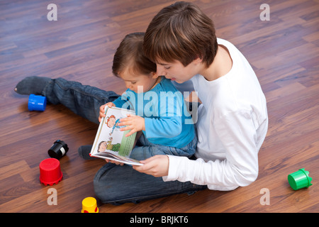 Ragazzo adolescente la lettura al fratello più giovane Foto Stock