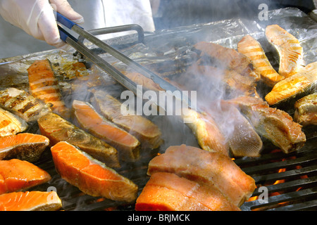 Un barbecue, una fiamma calda, e salmone essendo rivolta in fumo -- un weekend perfetto cookout o una vacanza su una lussuosa nave da crociera Foto Stock