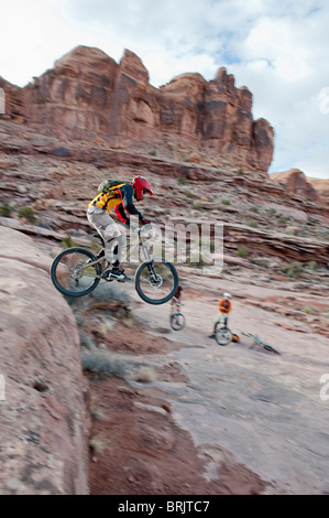 Una discesa con la mountain biker lancia off una goccia sulla Amasa torna Trail nel paese di Moab, UT. Foto Stock