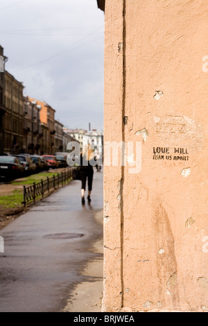 La donna a piedi passato Graffiti, "Love Will Tear Us Apart" di nuovo San Pietroburgo Russia Foto Stock