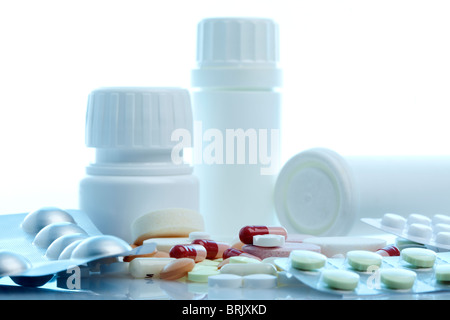 Pila di pillole e capsule in e fuori di confezioni blister e bottiglie, retroilluminazione azzurrognolo Foto Stock