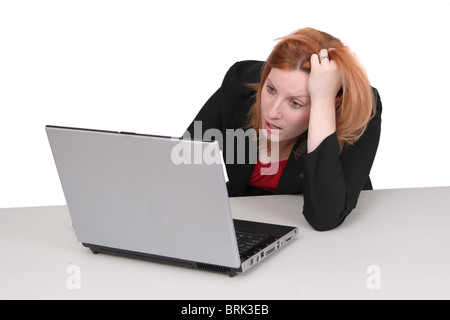 Un giovane adulto dai capelli rossi lady business in nero e rosso su bianco frustrati con il suo computer Foto Stock