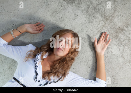 Bella ragazza appoggiata contro un muro di cemento Foto Stock