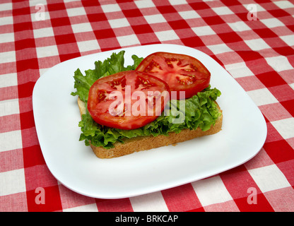 Incomplete blt sandwich su una piastra bianca con rosso sfondo selezionata Foto Stock