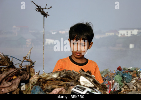 Un giovane bambino operaio ragazzo guarda attraverso la spazzatura per i sacchetti di plastica al pungo Meanchey discarica in Phnom Penh Cambogia. Foto Stock