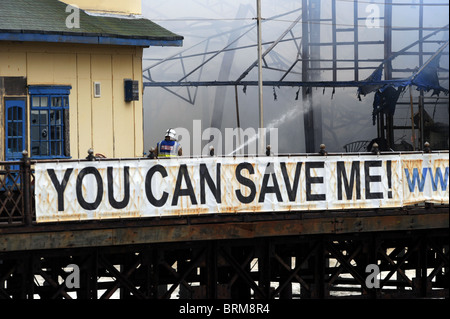 Hastings Pier smolders dopo un incendio doloso nelle prime ore di questa mattina lo lascia quasi completamente distrutta Foto Stock