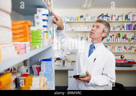 Il farmacista guardando il ripiano di pillole Foto Stock