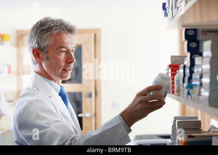 Il farmacista guardando pillola bottiglia Foto Stock