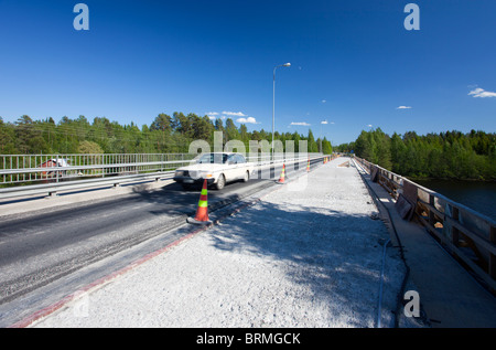 Una vettura che attraversa un ponte stradale dove la metà del ponte è in riparazione e asfalto è stato strappato via , Finlandia Foto Stock