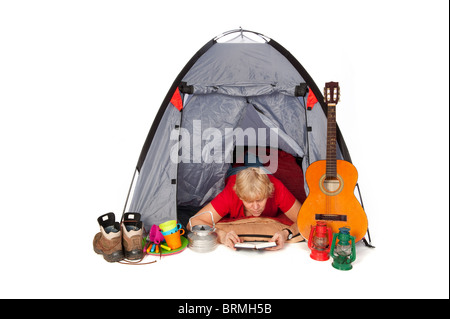 Donna anziana sta leggendo un libro nella tenda del campeggio Foto Stock