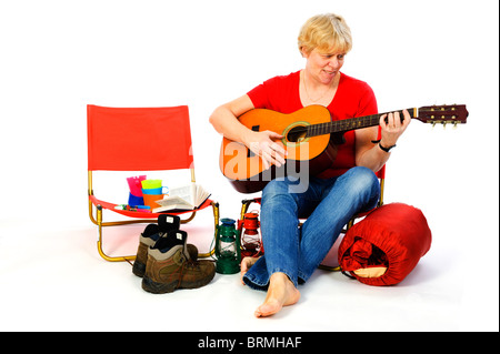 Senior womn è suonare la chitarra presso il campeggio Foto Stock