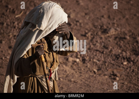 Una donna anziana con un mantello sopra la sua testa schermare gli occhi dal sole in Lalibela Foto Stock