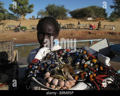 Una giovane ragazza africana dell'età di circa 14 anni di età la vendita di collane di perle Foto Stock