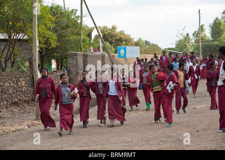 A scuola i bambini vestiti in divisa rossa per andare a casa dopo che la scuola è finita in Lalibela Foto Stock