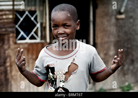 Ritratto di un giovane township ragazzo che indossa un strappata T-shirt Foto Stock