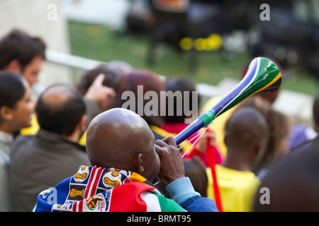 Vista posteriore di un sostenitore di calcio drappeggiati in un sudafricano di Coppa del Mondo di soffiatura di bandiera una vuvuzela durante la Coppa del Mondo 2010 Foto Stock