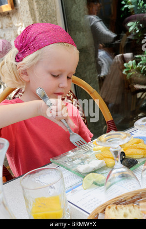 Foto di stock di un 4 anno vecchia ragazza godendo di un piatto di pesce e patatine fritte in un ristorante. Foto Stock