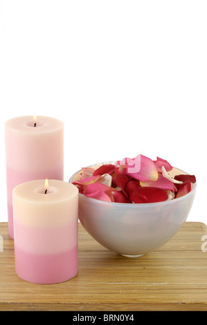 Candele accese fino nei pressi di petali di rosa in una ciotola Foto Stock