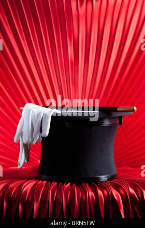 Il mago del Top Hat, Wand e guanti sul sipario rosso Foto Stock