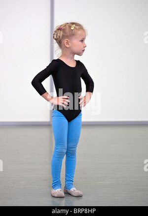 Piccola ragazza ginnasta in piedi in palestra Foto Stock