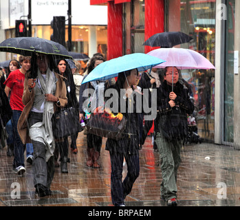 Gli amanti dello shopping a Londra in una fredda e piovosa giornata. Foto Stock