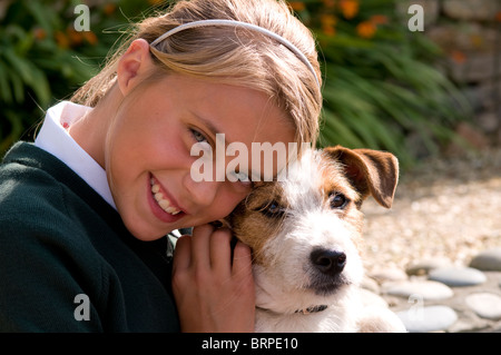 Ritratto di una scolaretta cuddling il suo cane Foto Stock