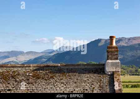 Il vecchio tetto di ardesia del tetto della casa e il camino che affaccia sulle montagne, Cumbria, England, Regno Unito Foto Stock