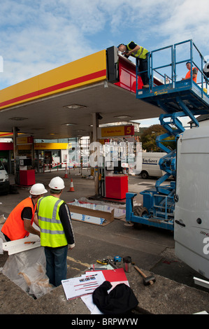 Operai il rinnovamento e il rebranding di un distributore di benzina Shell garage come Texaco , REGNO UNITO Foto Stock