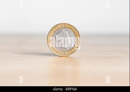 Due Pound coin isolato, in piedi sul bordo con ombra Foto Stock