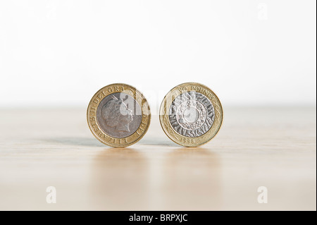 Due Pound coin isolato, in piedi sul bordo con ombra Foto Stock