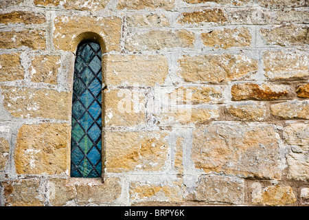 Close up di un tradizionale vecchio leaded arcuata la finestra della chiesa nel muro di pietra England Regno Unito Foto Stock