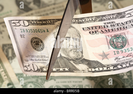 Pila di banconote americane con un cinquanta dollari essendo tagliato con un paio di forbici Foto Stock