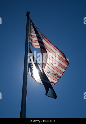 Stelle e strisce illuminate da dietro e il New York State flag su un pennone Foto Stock