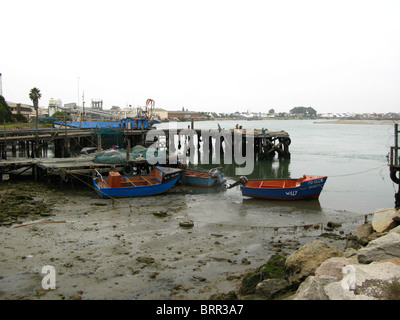La bassa marea nella zona del porto con barche da pesca Foto Stock