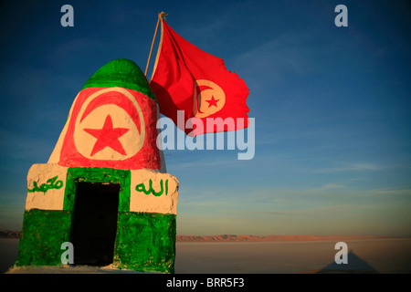 Bandiera tunisina vola su un piccolo monumento accanto al lago salato di Chott el-Jerrid Foto Stock