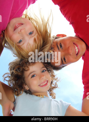 Al di sotto di vista di felice tre figli abbracciare abbracciarsi fotocamera sorridente