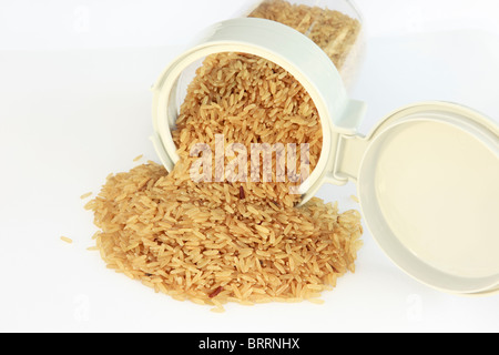 Pila di riso integrale crudo fuoriuscita di una plastica alimentare la pentola con un coperchio aperto top Foto Stock